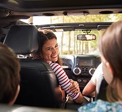 woman smiling at children in car