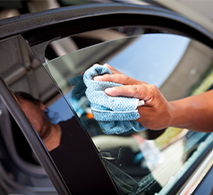 man cleaning car window with a microfiber cloth 